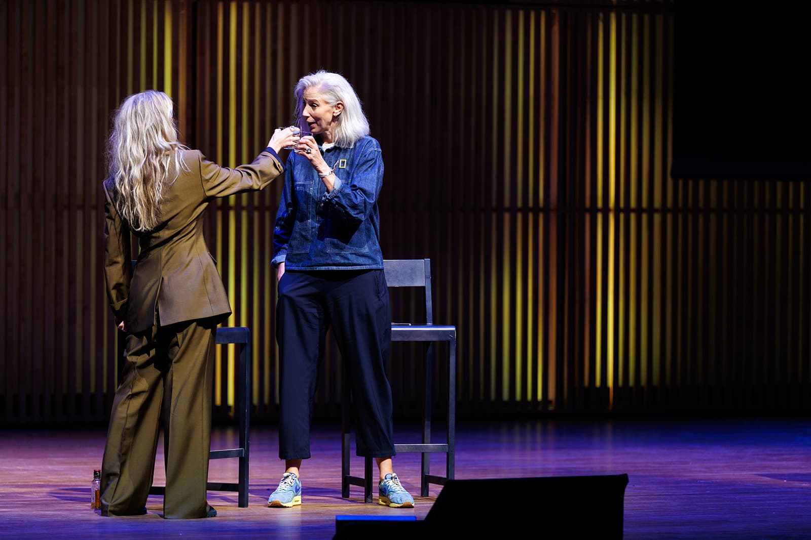 Alice Aedy handing Sophie Darlington a microphone on stage at the National Geographic Summit