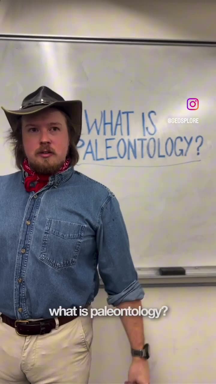 Matt, in a ranger hat and denim shirt, standing before a whiteboard that reads “What is paleontology?”